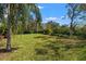 Expansive backyard with lush green grass, mature trees, and neatly trimmed hedges on a sunny day at 8445 Lone Eagle Way, Sarasota, FL 34241