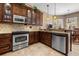Kitchen features dark wood cabinets, stainless steel appliances, granite countertops, and ample storage space at 8445 Lone Eagle Way, Sarasota, FL 34241