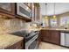 Gourmet kitchen boasts custom dark wood cabinets, granite countertops, stainless steel appliances, and plenty of natural light at 8445 Lone Eagle Way, Sarasota, FL 34241