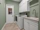 Well-lit laundry room features a utility sink, washer, dryer, and ample overhead cabinet storage at 8445 Lone Eagle Way, Sarasota, FL 34241