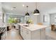 Bright, modern kitchen with an island, pendant lights, and open to the living room and dining area at 8641 Rain Song Rd, Sarasota, FL 34238