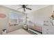 Bright Bedroom with a crib, comfortable chair, and a delightful window seat filled with books and natural light at 8907 White Sage Loop, Lakewood Ranch, FL 34202