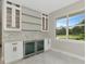 Wet bar with white cabinetry, dual beverage refrigerators, glass shelving, and a backyard view at 920 Lena Ln, Sarasota, FL 34240