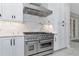 Stainless steel kitchen range with custom hood and white cabinets with marble backsplash providing a modern aesthetic at 920 Lena Ln, Sarasota, FL 34240