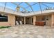 Large, screened-in patio with stone floors, an outdoor kitchen, and white Adirondack chairs at 920 Lena Ln, Sarasota, FL 34240