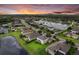 Sunset aerial showcasing a beautiful neighborhood with well-maintained lawns, a serene lake, and lush greenery at 9927 58Th E St, Parrish, FL 34219