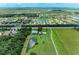 Expansive aerial view of a residential area with a pond, green fields, and tree lined streets at 12851 24Th Street E Cir, Parrish, FL 34219