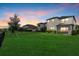 Picture of a well-maintained backyard with green grass, black fencing, and a beautiful sunset sky at 16419 Paynes Mill Dr, Bradenton, FL 34211
