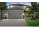 Two-story gray home featuring a gray garage door, tropical landscaping, and a paver driveway at 16419 Paynes Mill Dr, Bradenton, FL 34211