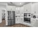 Bright kitchen featuring white cabinets, stainless steel appliances, gray subway tile backsplash, and wood-look floors at 16419 Paynes Mill Dr, Bradenton, FL 34211