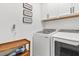 Functional laundry room with modern washer and dryer units, cabinets, and a wooden shelving unit at 16419 Paynes Mill Dr, Bradenton, FL 34211