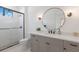 An elegant bathroom features a gray vanity, framed circular mirror and a glass shower at 16511 Cornwall Ln, Lakewood Ranch, FL 34202