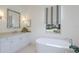 An elegant bathroom with a soaking tub, white marble floors, vanity and striped shades at 16511 Cornwall Ln, Lakewood Ranch, FL 34202