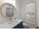 Cozy bathroom featuring a round mirror, blue vanity, and window for natural light at 16511 Cornwall Ln, Lakewood Ranch, FL 34202