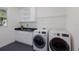 Well-lit laundry room with modern washer and dryer, sink with dark countertop, and white cabinets at 16511 Cornwall Ln, Lakewood Ranch, FL 34202