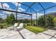 Screened-in patio with a mini-golf area, lounge chairs, and landscaping at 16511 Cornwall Ln, Lakewood Ranch, FL 34202