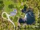 A lush aerial view of a sprawling property featuring a house, pool, and serene pond surrounded by mature trees and greenery at 21705 67Th E Ave, Bradenton, FL 34211