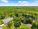 Overhead view of home with swimming pool nestled among a lush green environment with a large pond at 21705 67Th E Ave, Bradenton, FL 34211