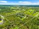 An aerial view showcases the vast property with abundant greenery and trees, a tranquil pond, and picturesque surroundings at 21705 67Th E Ave, Bradenton, FL 34211