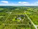 Aerial view displays the large property featuring a pond, lush trees, and a defined boundary, bordered by surrounding roads at 21705 67Th E Ave, Bradenton, FL 34211