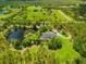 Stunning aerial view of a sprawling property featuring a serene pond, mature trees, and a lovely home at 21705 67Th E Ave, Bradenton, FL 34211
