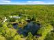 Aerial view reveals lush trees, a serene pond, and a charming house with a pool nestled within the expansive property at 21705 67Th E Ave, Bradenton, FL 34211