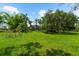 Expansive front yard with lush green grass and mature trees, offering a serene and private setting at 21705 67Th E Ave, Bradenton, FL 34211