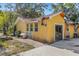 Back exterior view of a yellow home with a sliding glass door and a large window showcasing a spacious backyard at 218 32Nd W St, Bradenton, FL 34205