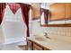 Cozy bathroom featuring vanity sink, patterned red curtains, and a tiled bathtub and shower at 218 32Nd W St, Bradenton, FL 34205