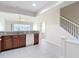 Open kitchen features granite countertops, wood cabinets, stainless sink, and access to the bathroom and stairs at 26548 Castleview Way, Wesley Chapel, FL 33544
