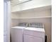 The laundry room includes a side-by-side washer and dryer and shelves for storage at 26548 Castleview Way, Wesley Chapel, FL 33544
