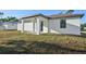 Side angle of home's exterior features a covered patio and grassy area at 2813 Sally Ln, North Port, FL 34286