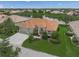Aerial view of beige single-Gathering home with red tile roof and a lake view surrounded by green grass and lush landscaping at 2937 Seasons Blvd, Sarasota, FL 34240