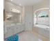 Bright bathroom features double vanity, soaking tub beneath arched window, and tiled flooring at 2937 Seasons Blvd, Sarasota, FL 34240