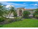 Well maintained front yard featuring lush grass, mature palm trees, and landscaped garden beds leading to a beige home at 2937 Seasons Blvd, Sarasota, FL 34240