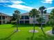 Inviting backyard featuring a well-maintained lawn and mature palm trees near a building with screened lanais at 318 Winding Brook Ln # 104, Bradenton, FL 34212