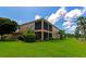 A backyard of a two story home with a screened in lanai with a large lawn and tropical landscaping at 318 Winding Brook Ln # 104, Bradenton, FL 34212