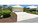Bright yellow home featuring a white garage and a long patterned driveway at 340 Bermuda Ct # 5, Venice, FL 34293