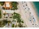Overhead view of beachside homes and the sandy shoreline with colorful umbrellas and clear turquoise waters at 3720 Gulf Dr, Holmes Beach, FL 34217