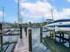 Dock with boat lift and boat, against a backdrop of picturesque waterfront homes under a bright sky at 3954 Hamilton Club Cir # 14, Sarasota, FL 34242