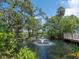 Scenic view of a lush pond with a fountain, surrounded by mature trees and colorful foliage at 3954 Hamilton Club Cir # 14, Sarasota, FL 34242