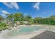 Relaxing backyard pool with lush tropical landscaping, sunny sky, chairs, and umbrella at 4396 Pasadena Cir, Sarasota, FL 34233
