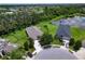 Aerial view of a home with a well-manicured lawn, mature trees, and proximity to a tranquil lake at 4716 98Th E Ter, Parrish, FL 34219
