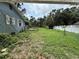 Backyard view of a quaint home with a wooden deck and overgrown grass, enclosed by a white picket fence at 5124 17Th Street E Ct, Bradenton, FL 34203
