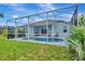 View of a screened in pool from backyard with green grass and landscaping at 5139 50Th W Ave, Bradenton, FL 34210