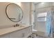 Bright white bathroom featuring a shower with blue curtain, a round mirror, and gray countertops at 5139 50Th W Ave, Bradenton, FL 34210