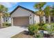 Home exterior showing a two-car garage and a landscaped yard with flowering bushes and palm trees at 5981 Amberly Dr, Bradenton, FL 34208