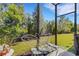 View from the screened in patio to the backyard with lush landscaping and a butterfly designed bench at 5981 Amberly Dr, Bradenton, FL 34208