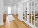 Bright hallway with hardwood floors leads to a front door and office with glass French doors at 6120 115Th E Ave, Parrish, FL 34219