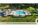 Aerial view of the pool area with blue pool, lounge chairs, palm trees, and cabana overlooking a pond at 6120 115Th E Ave, Parrish, FL 34219